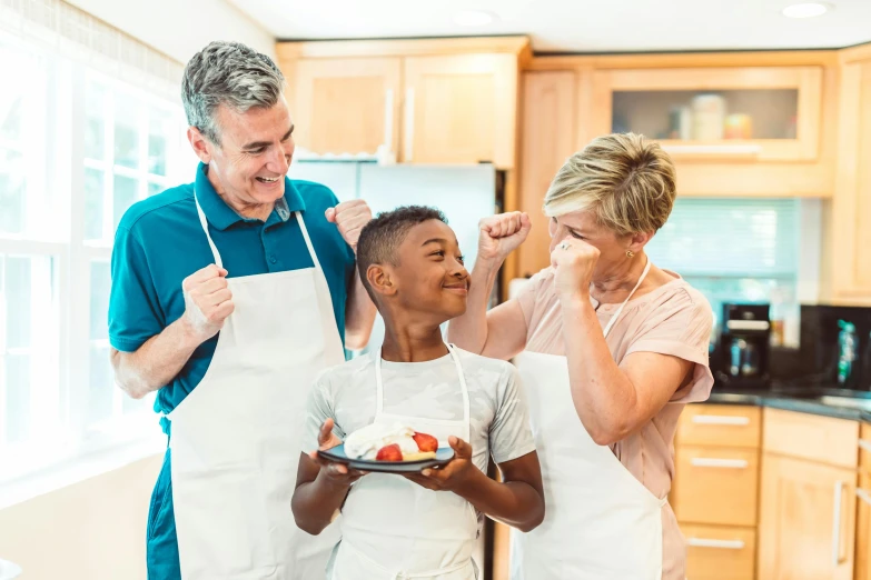 three people in the kitchen holding up plates and looking at each other