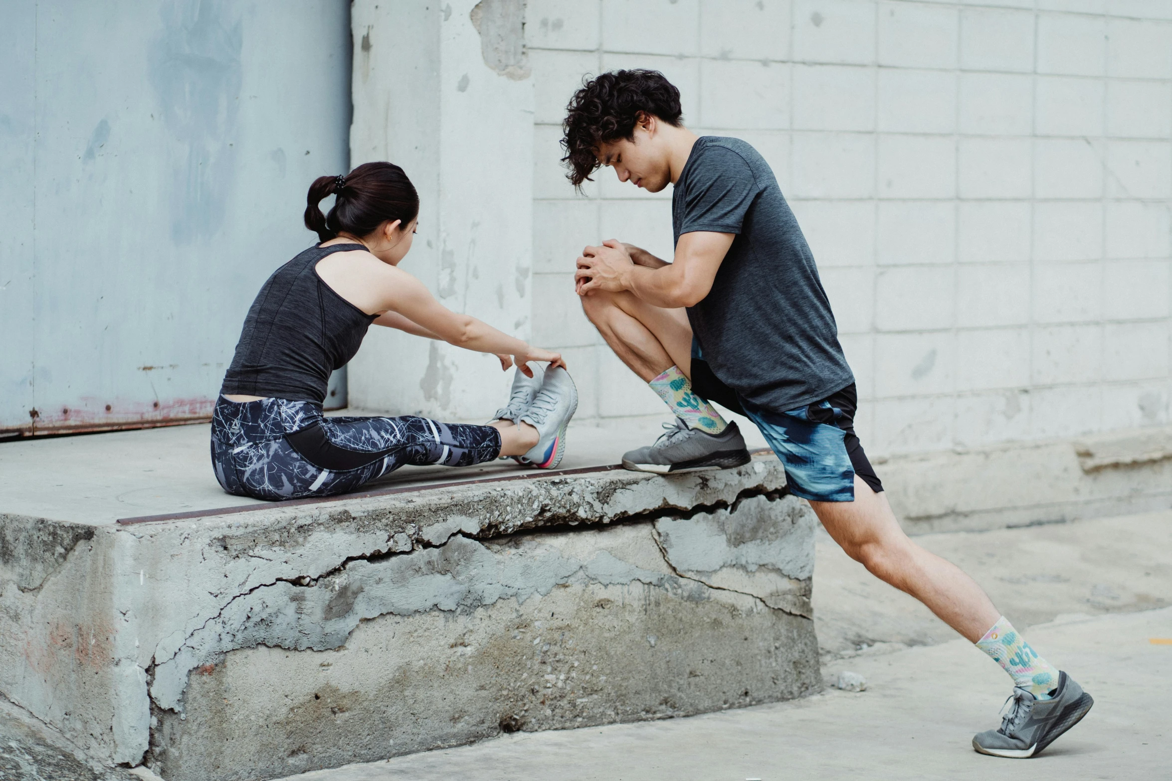 a couple of people sitting on a ledge near a building