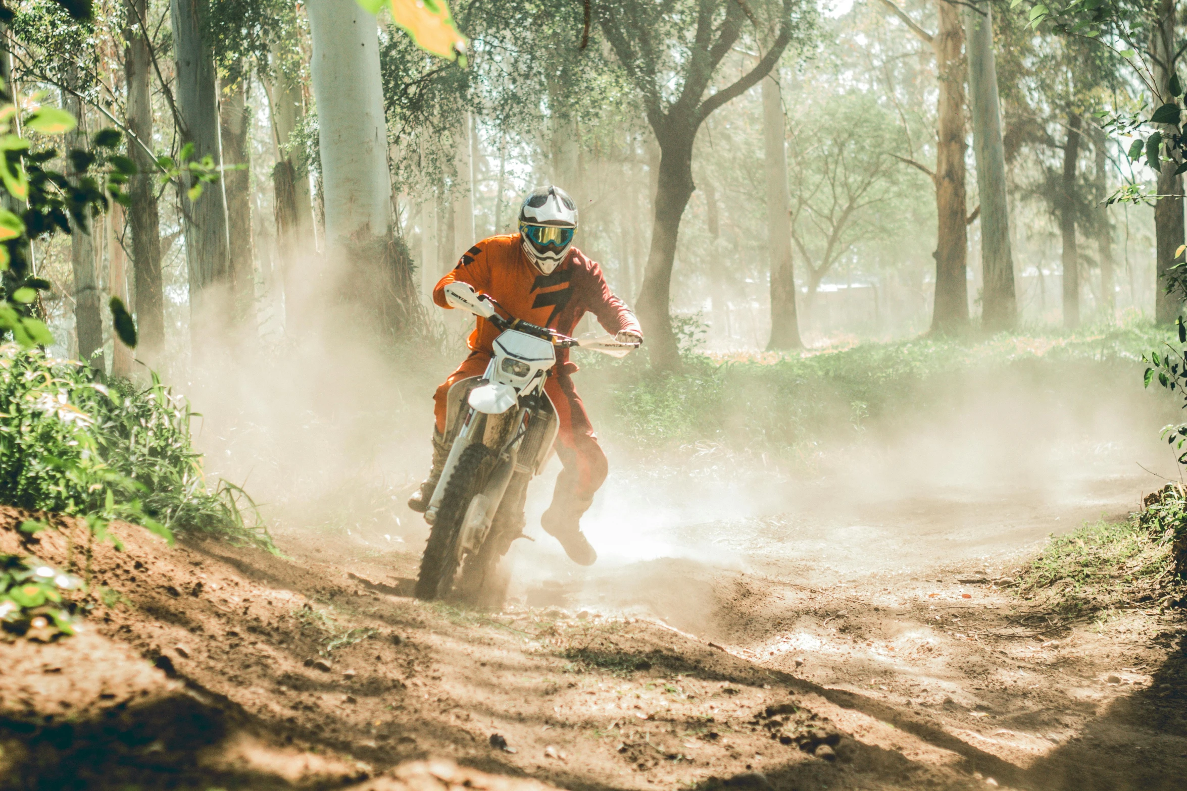 a man riding a dirt bike through a forest