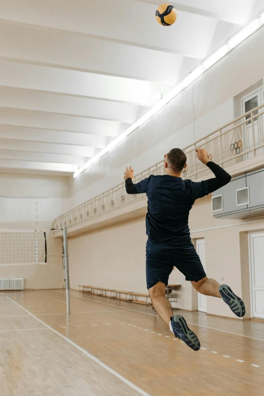 a man in an indoor basketball court jumping for the ball