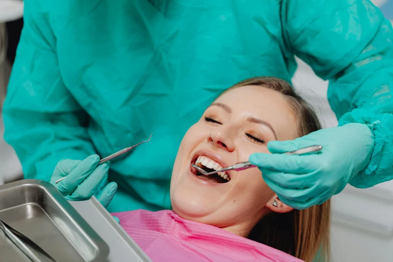 an attractive woman having her teeth brushed while sitting in the dentist chair