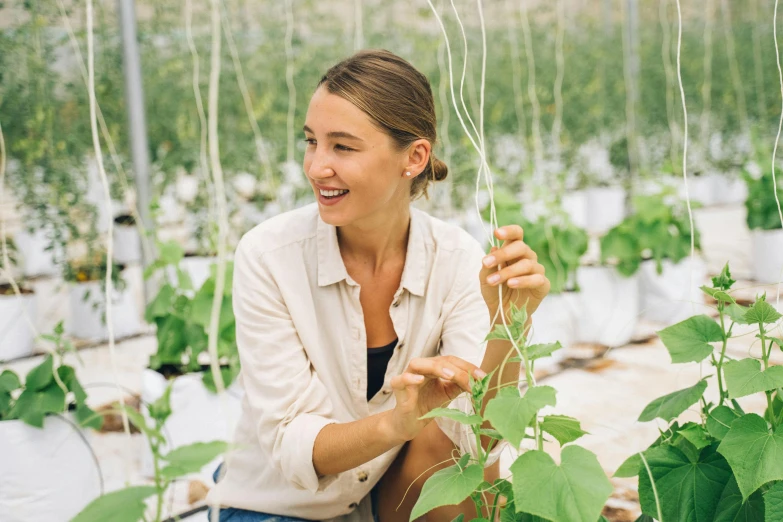 the smiling lady is putting her thumb in the plants