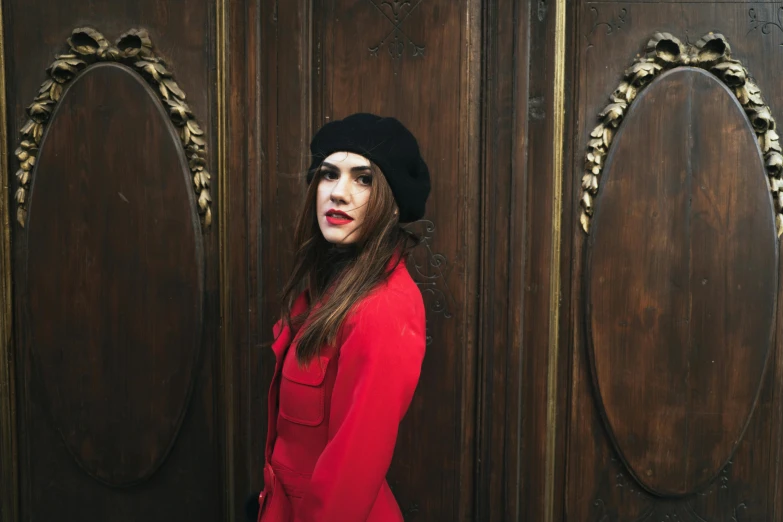 a woman wearing a beanie standing in front of a doorway