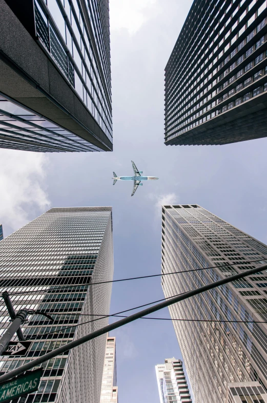 the airplane is flying between the tall buildings