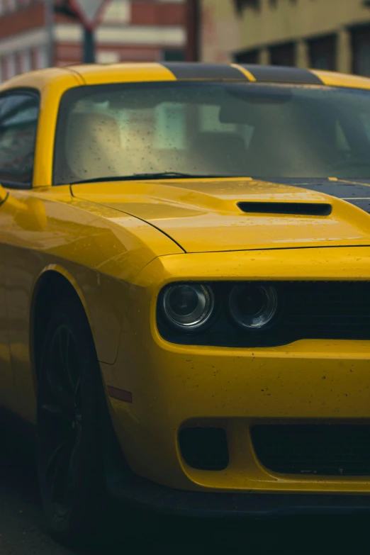 a close up of a yellow car parked near some buildings