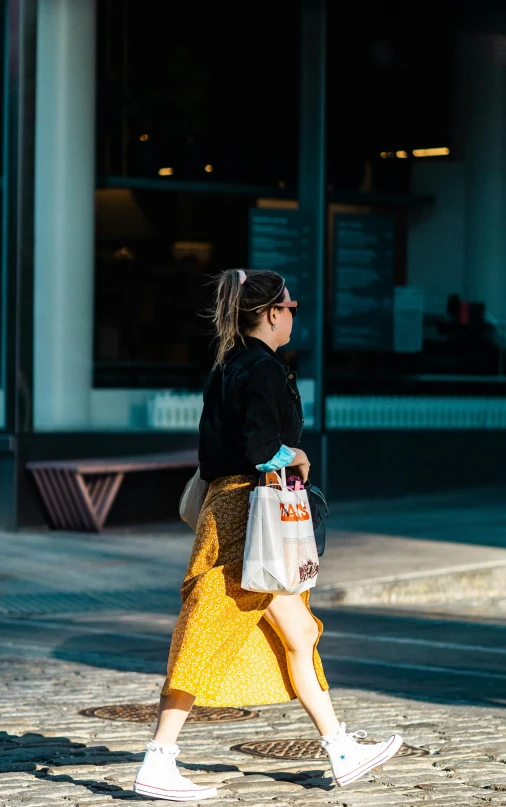 woman carrying grocery bag walking on sidewalk in city