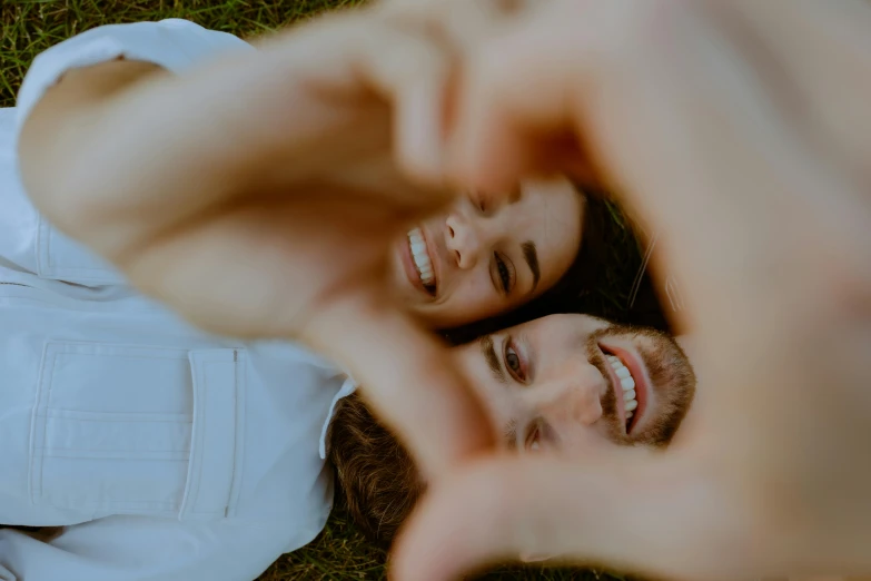 a couple laying in the grass making a heart