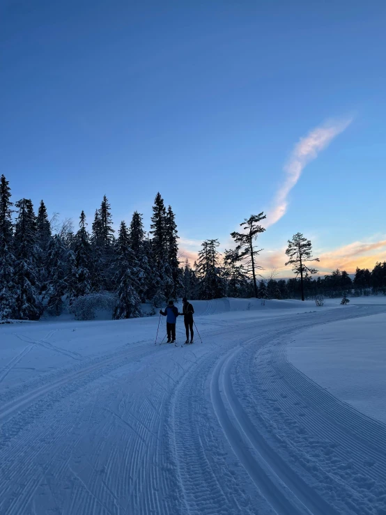 two people riding skis on a snow covered slope