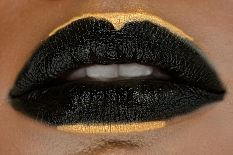 a woman's lips are black with gold around the tip