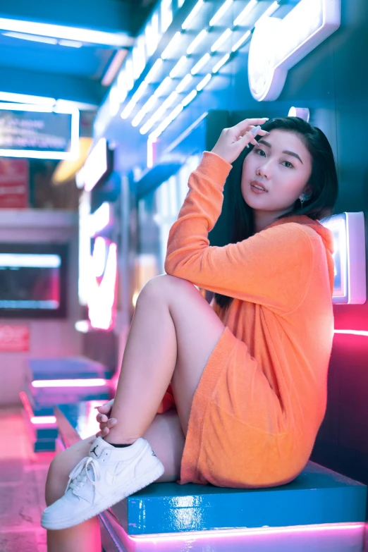 a woman sitting on a blue bench near neon lights