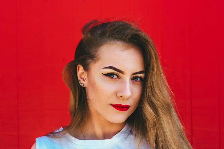 a woman with long hair wearing a shirt and looking at the camera