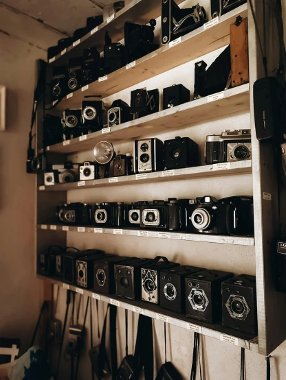 many old cameras are stored on the shelving in this room