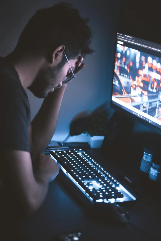 a man looking at the keyboard and monitor