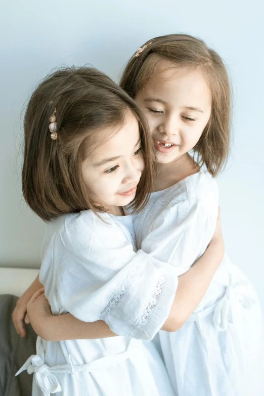 a close up of two girls hugging on the bed