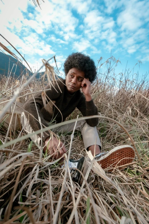 a man sitting in a field with a cellphone to his ear