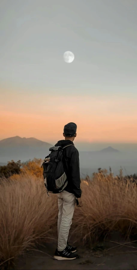 a person in the mountains watching a full moon