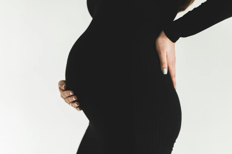 a pregnant woman wearing black dress looking at the camera