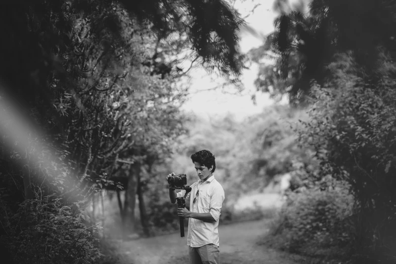 a man holding a camera in his hands in the woods