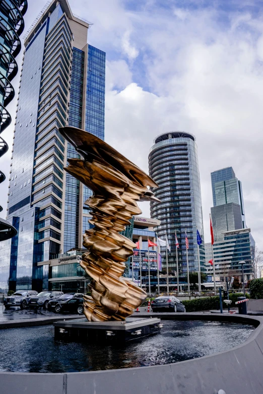 a metal sculpture sitting in front of tall buildings