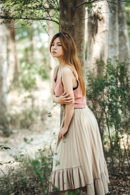 a woman in the forest standing by a tree