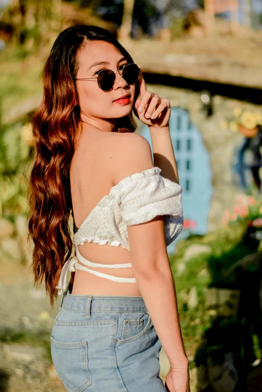 an asian woman with sun glasses on holding her hair up in a half - up ponytail