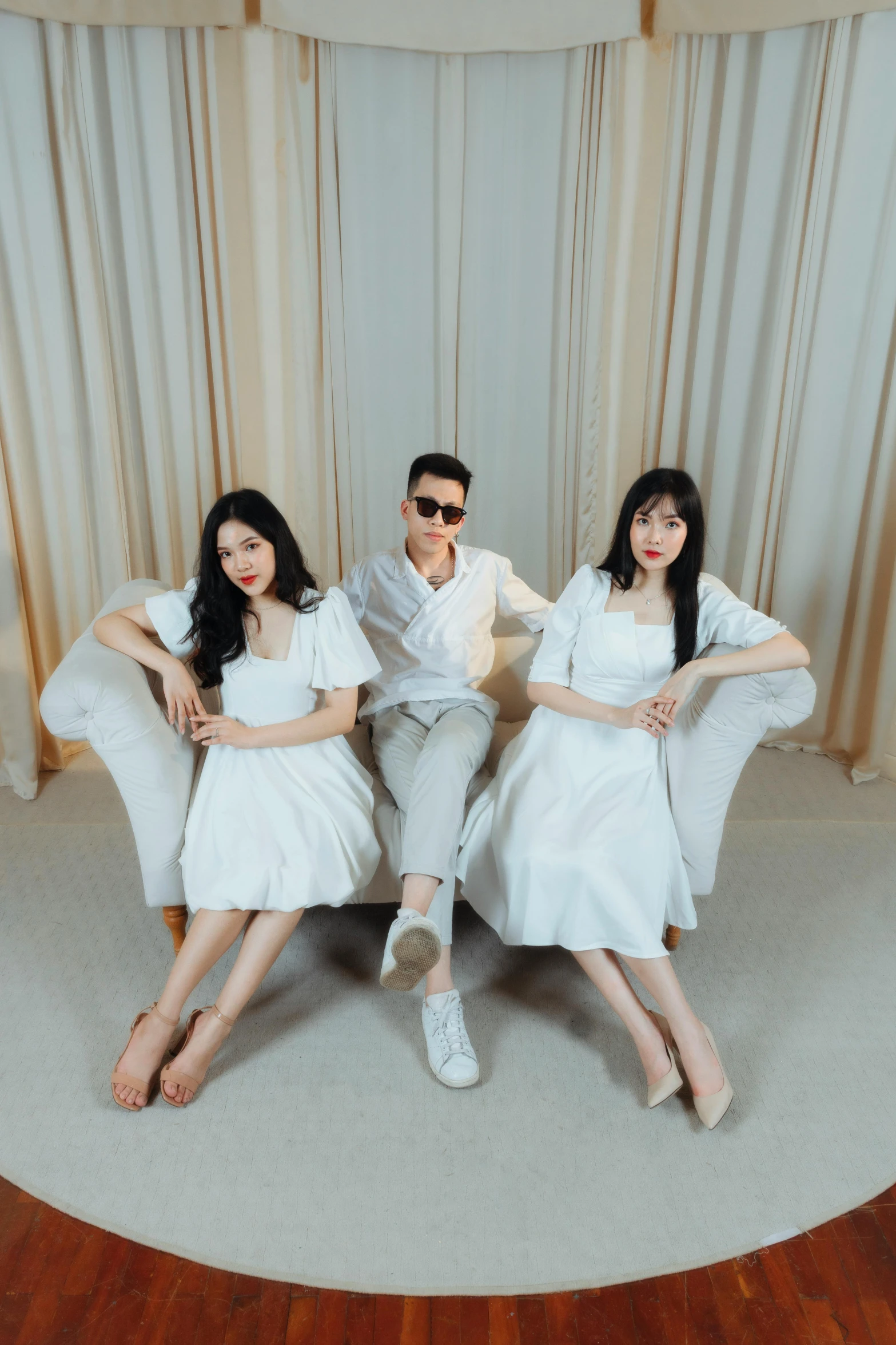 three people posing on top of a white couch