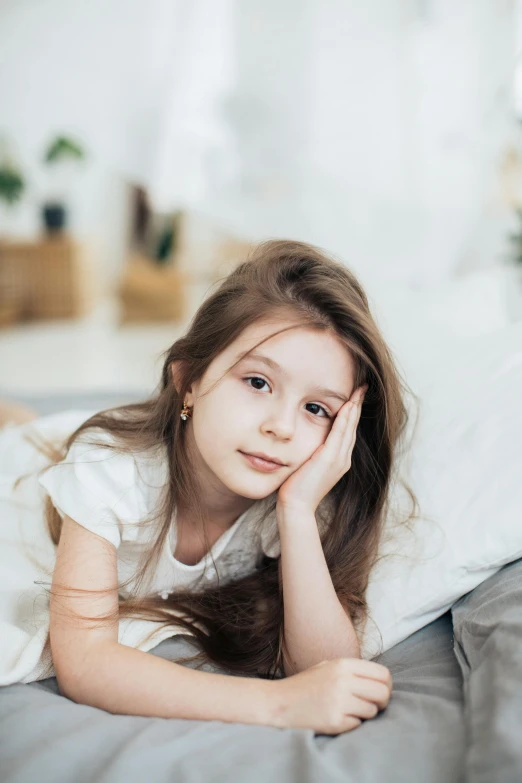 a girl sitting on a bed with her hands behind her head