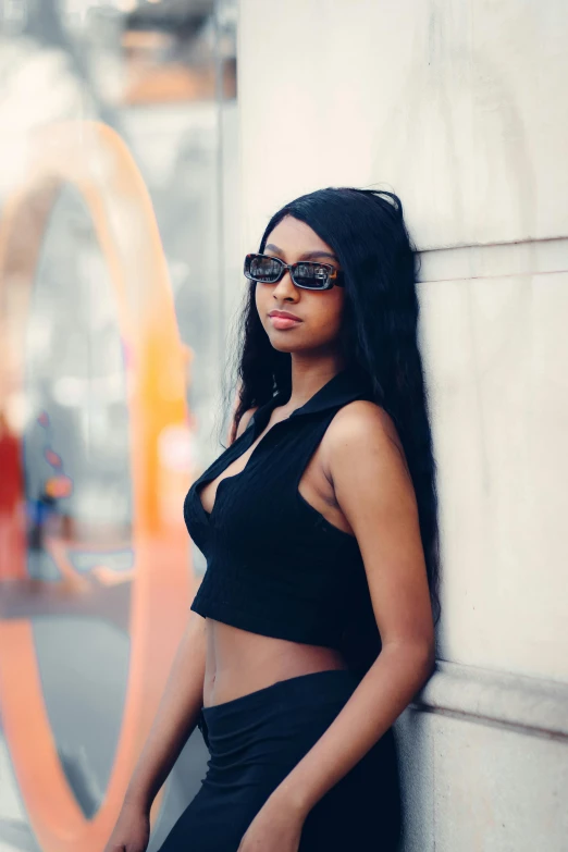 a woman leaning against a wall wearing black