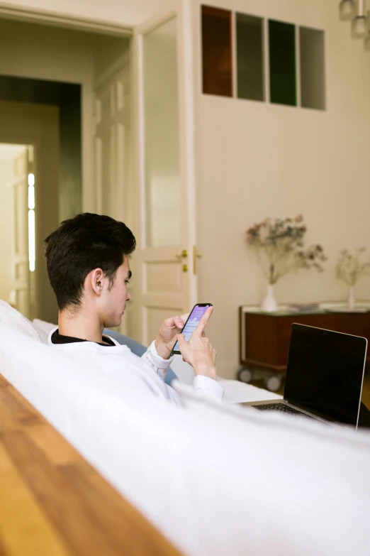 a man sitting on top of a bed next to a laptop computer