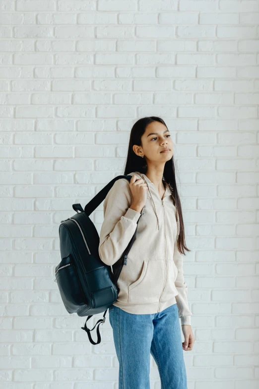 a woman holding onto a handbag by a white brick wall