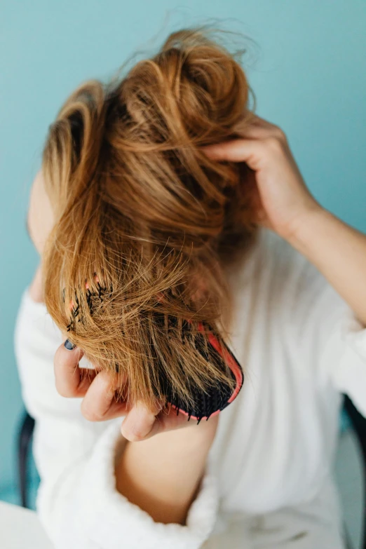 a woman combing her hair with a comb