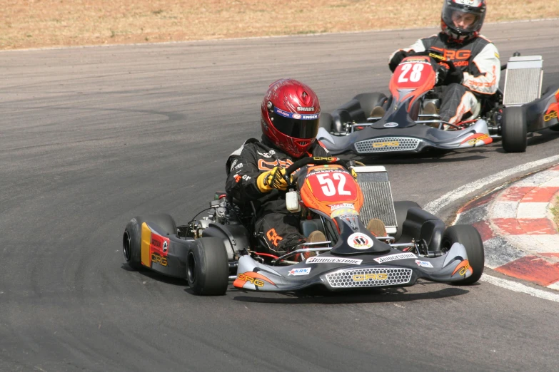 two go kart riders driving along a track on top of each other