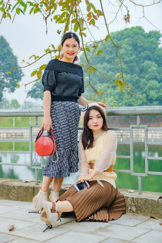 two women sitting on steps in front of some trees