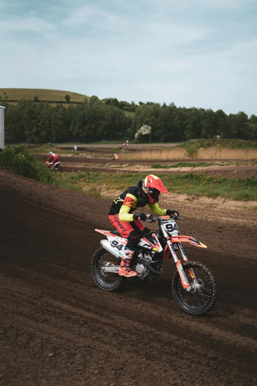 a man riding on the back of a dirt bike down a dirt field