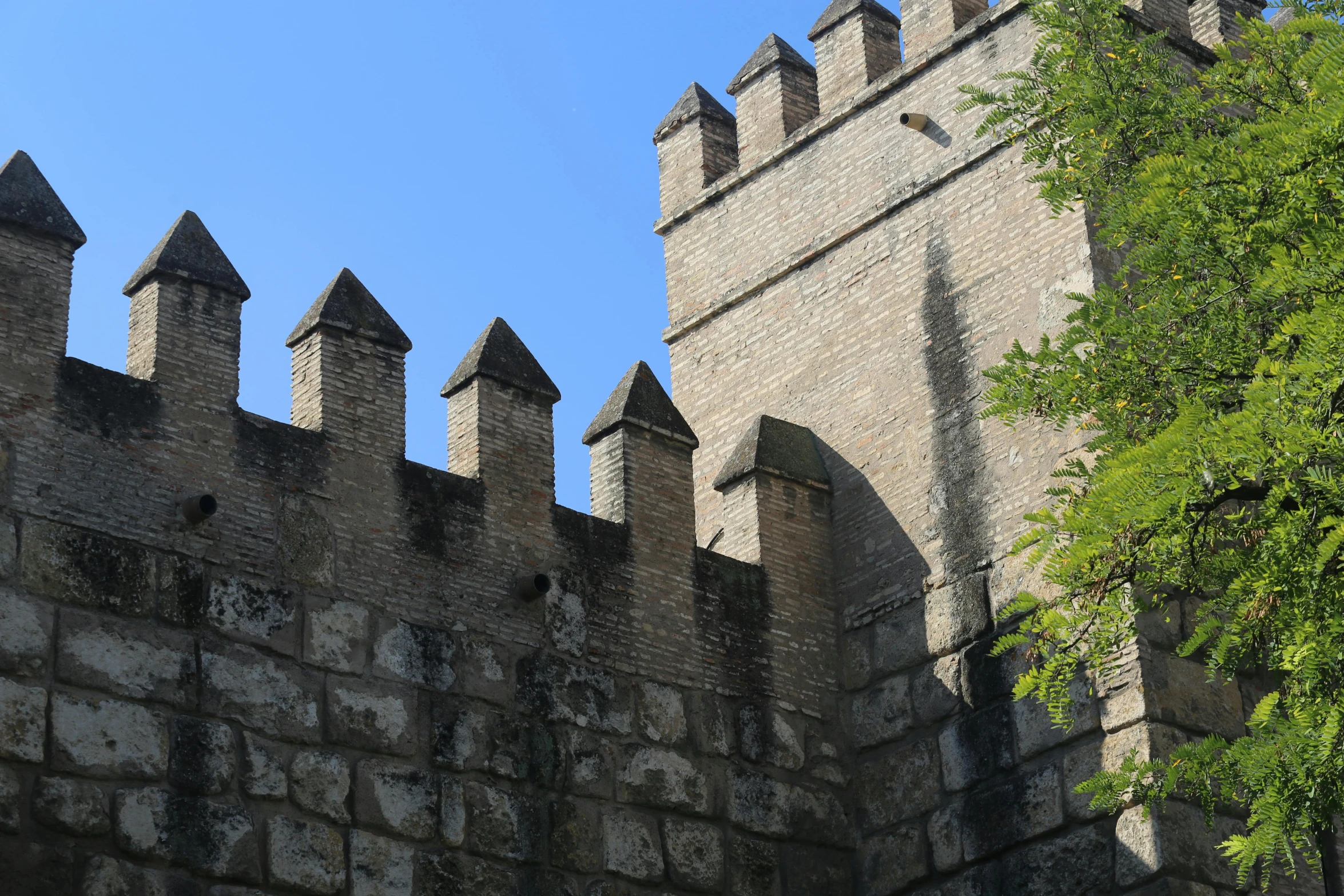 an ancient stone castle wall with large chimneys