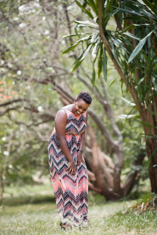 a woman wearing a dress walking through the woods