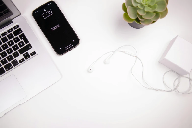 a pair of headphones, cellphone and a laptop on a table