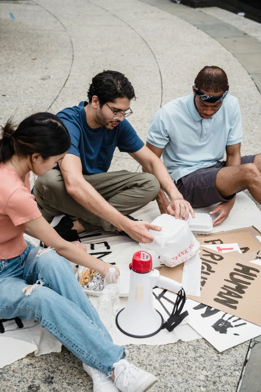 four people sitting on the ground next to some soda bottles