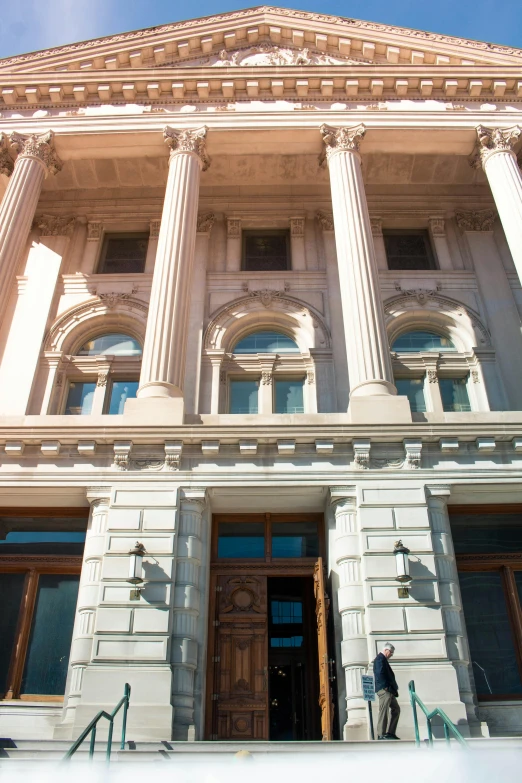 the front door to an old style courthouse building with a man walking in front