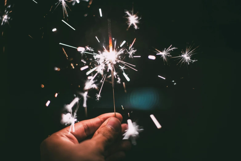 a person holding fireworks on a dark background