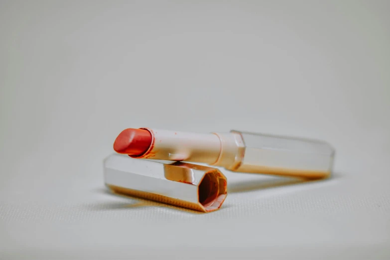 two empty bottles of lipstick sitting on a white surface