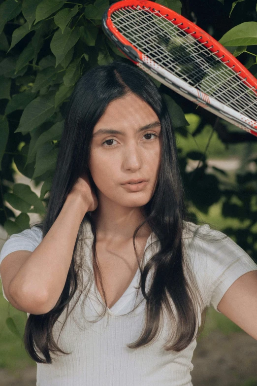 a young woman wearing a t shirt holding up a tennis racquet