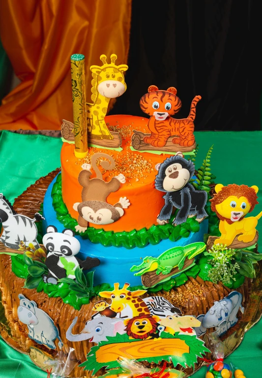 a tiered birthday cake decorated with jungle animals and other jungle animals