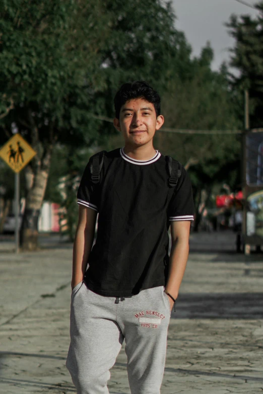 a young man stands in the street, with his skateboard