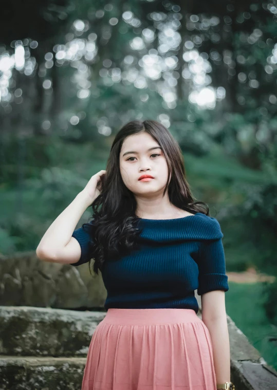 an asian woman in a blue shirt and pink skirt