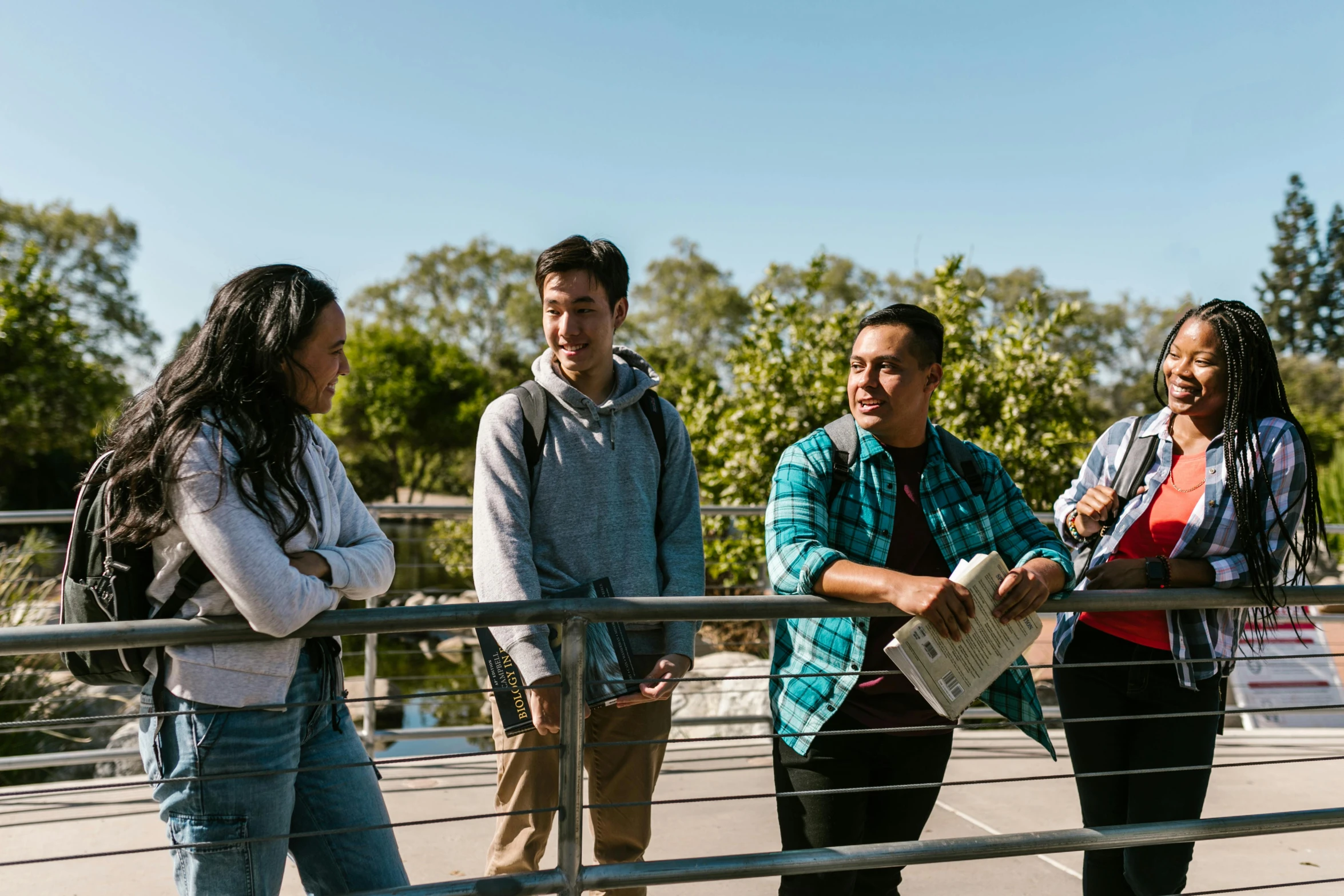 four people are standing on a bridge and looking at soing