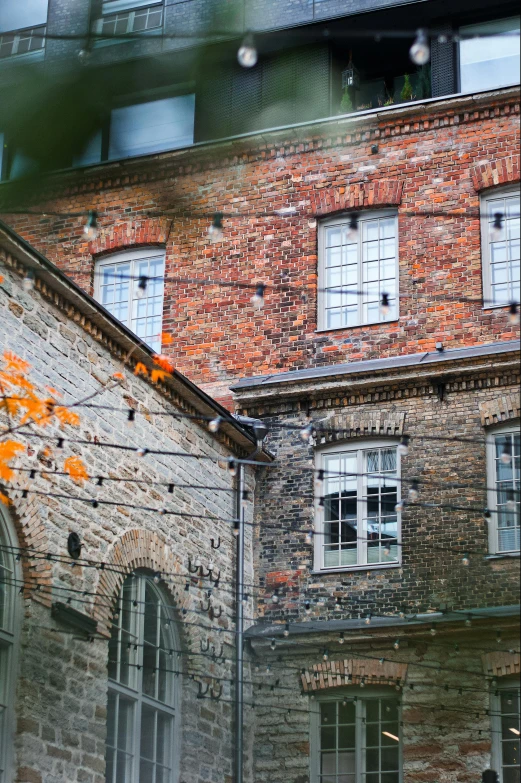 a brick building with two stories and a red tree outside