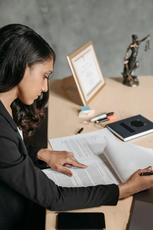 a young woman sitting at a desk reading a book