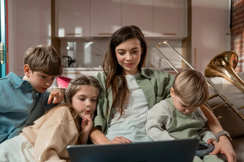 two children and their mother using a laptop