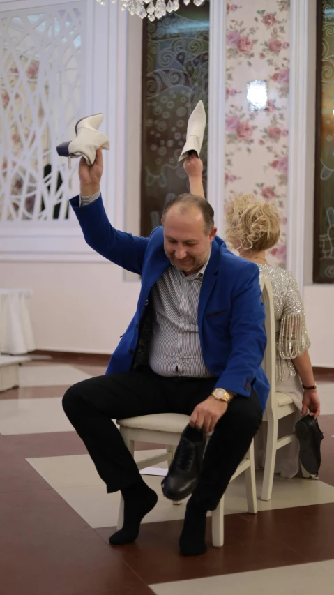 a man in a blue jacket is holding up a pair of white shoes